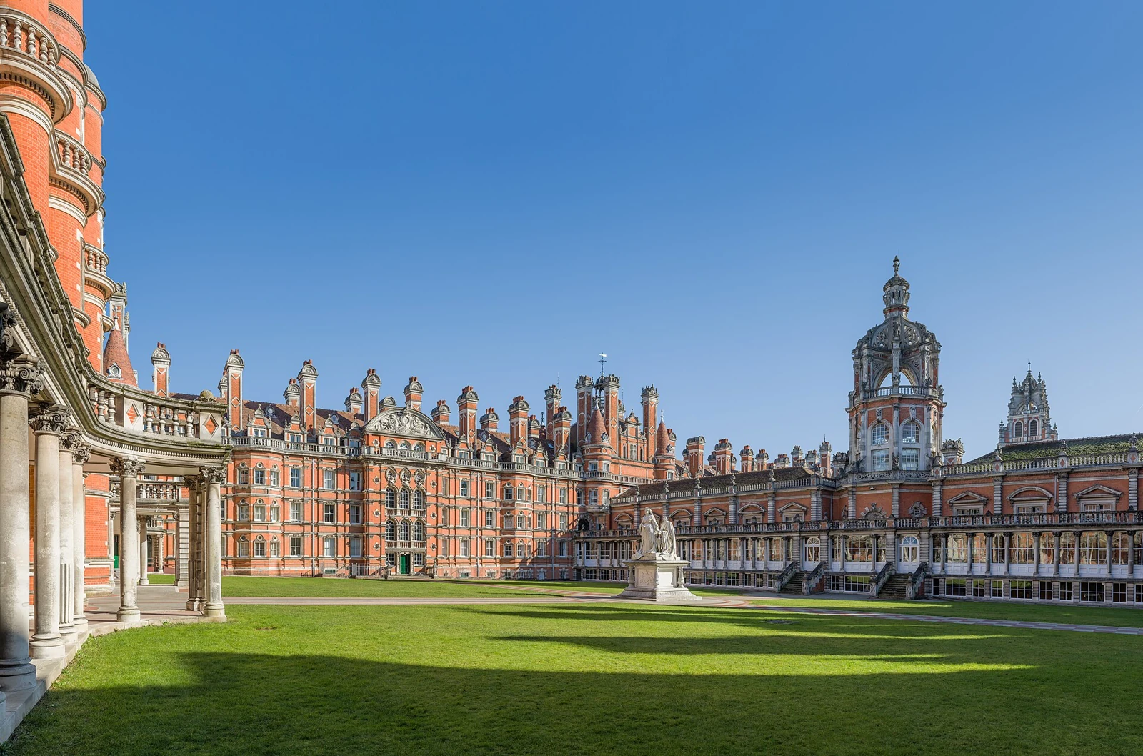 Sunlit red-brick university buildings and green courtyard at Royal Holloway, UK